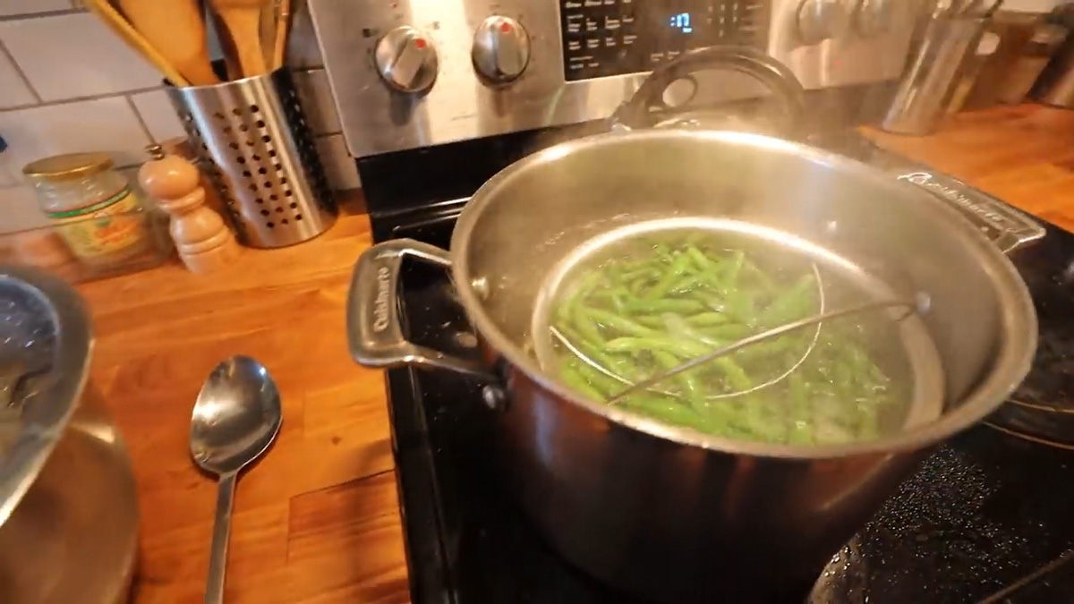 Green beans being blanched in a pot of boiling water.