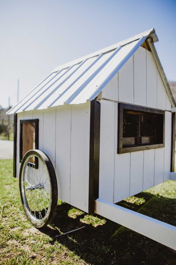 A white with black trim mobile chicken coop.