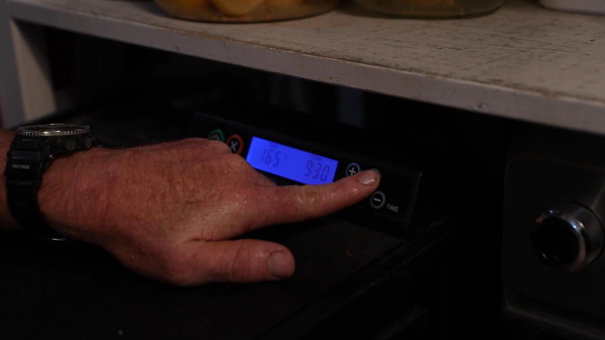 A man setting a dehydrator to 165 degrees F for nine hours and thirty minutes.