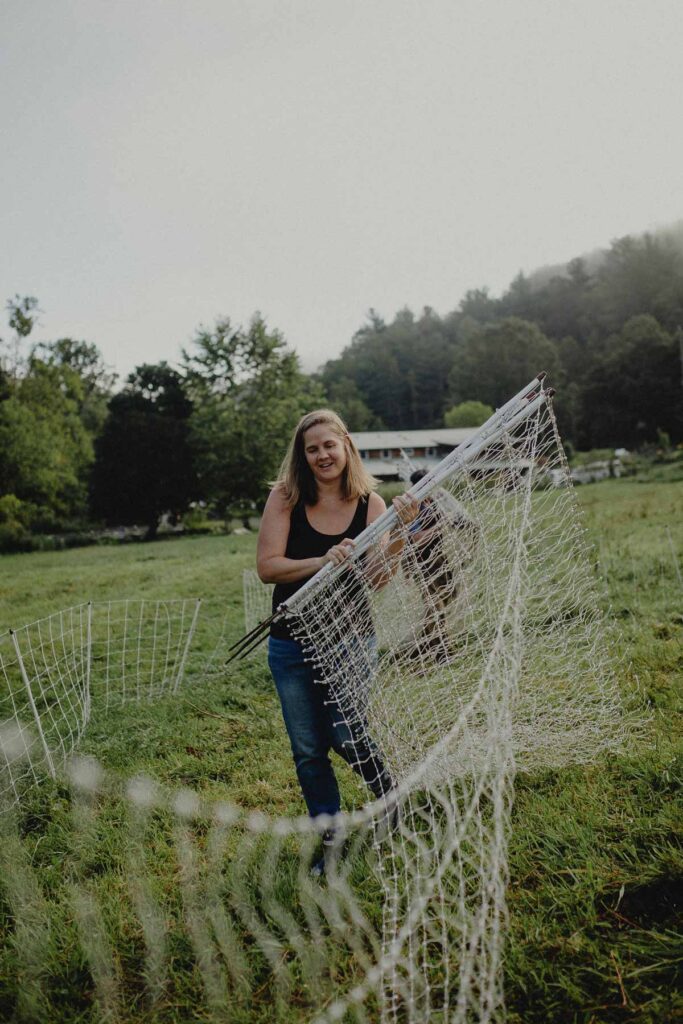 A woman gathering up electric fence netting.