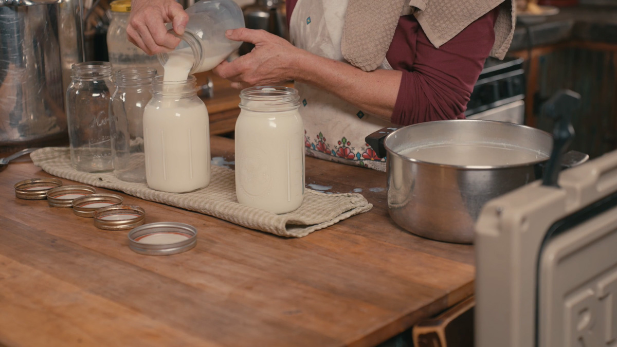 A woman pouring milk into jars.