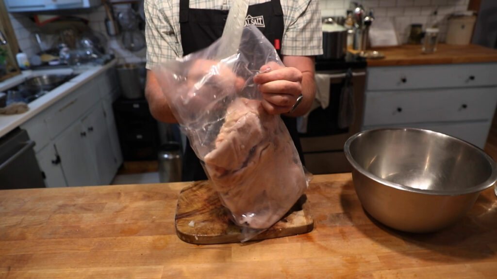 A man cutting open a bag of pork skin.