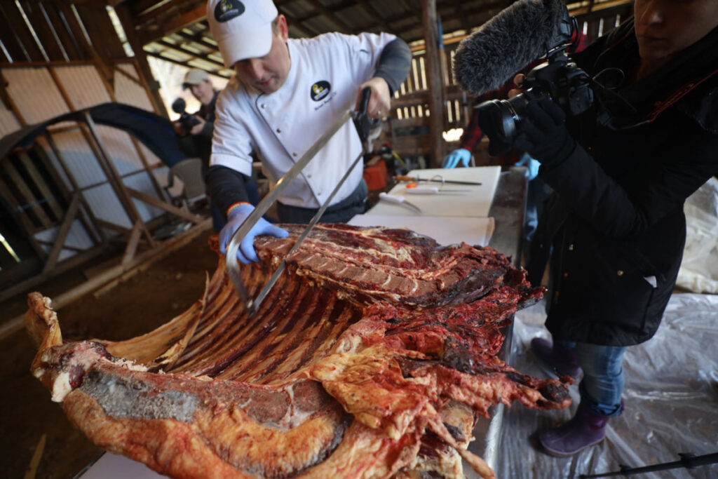 A man butchering a cow with a saw.