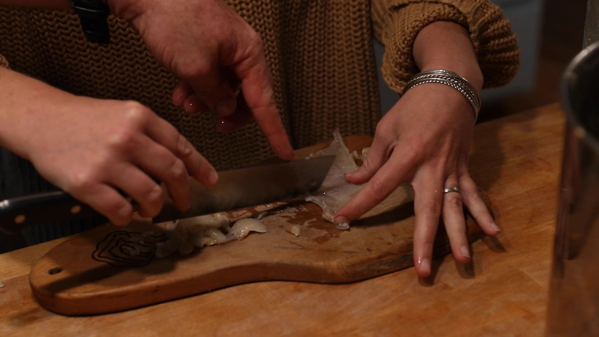 A woman scraping the extra fat off of pork skin.