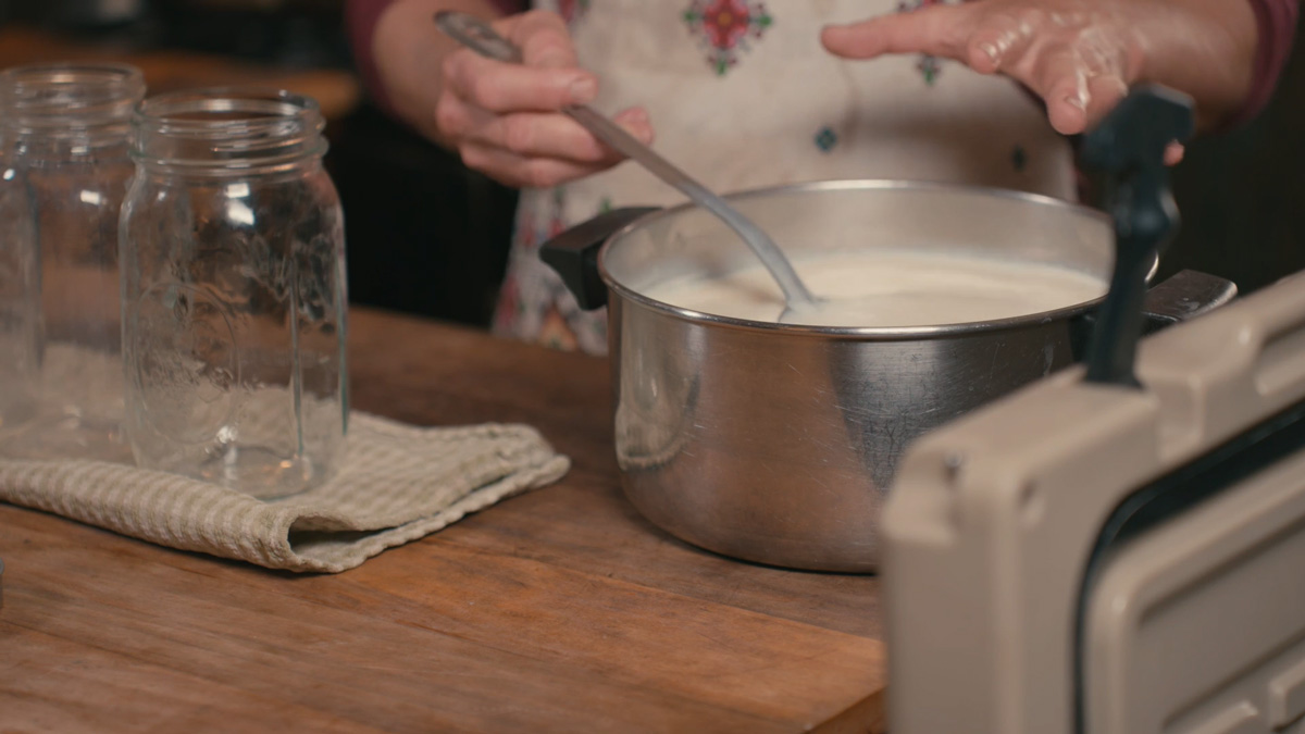 A woman stirring a pot of milk.