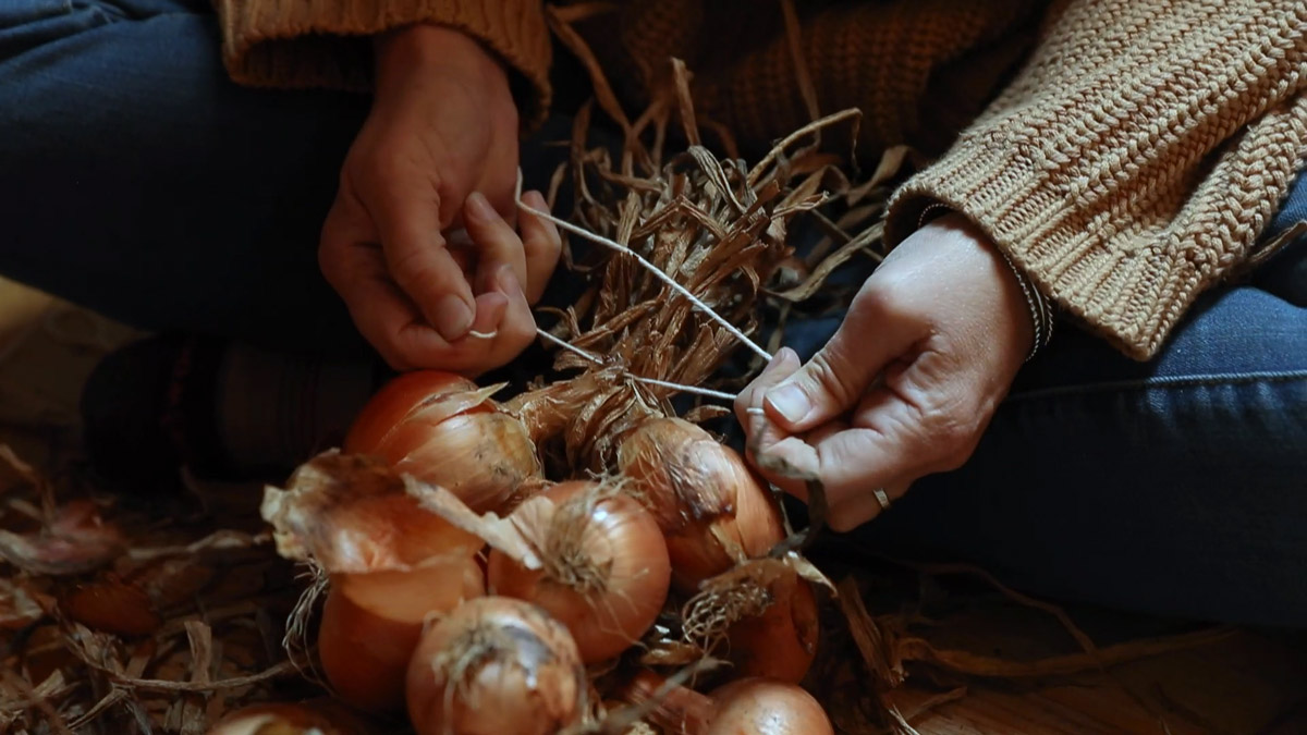 A woman braiding onions.