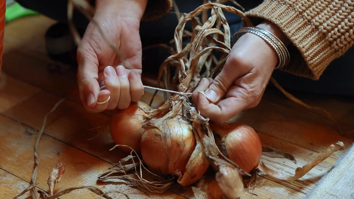 A woman braiding onions.