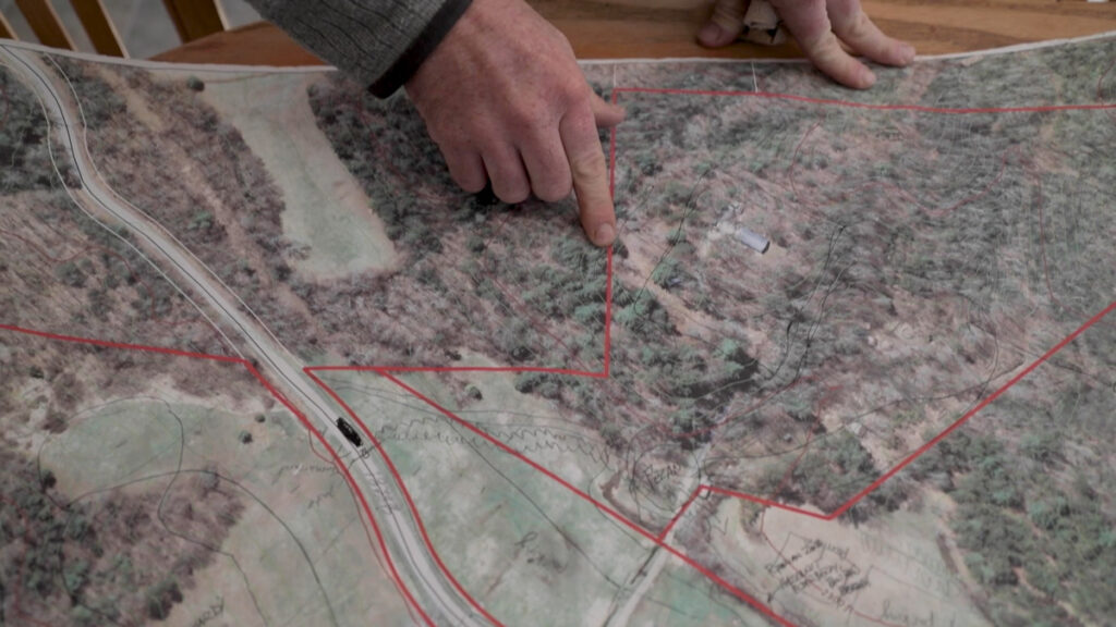 A man's hand pointing to a property GIS map.