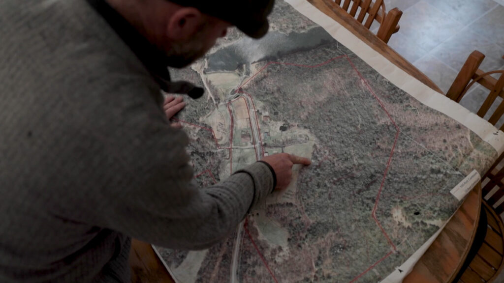 A man's hand pointing to a property GIS map.