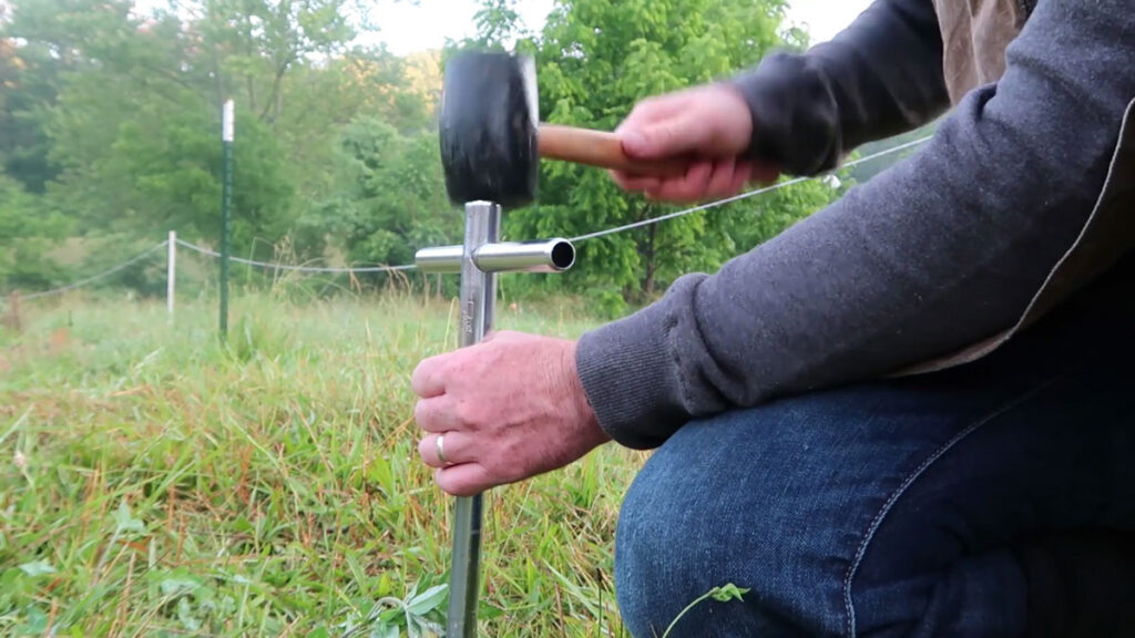 A man hammering in a soil probe into the soil.