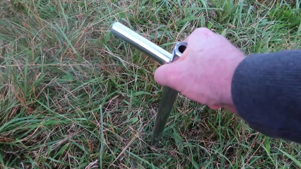 A man pushing a soil probe into the ground.